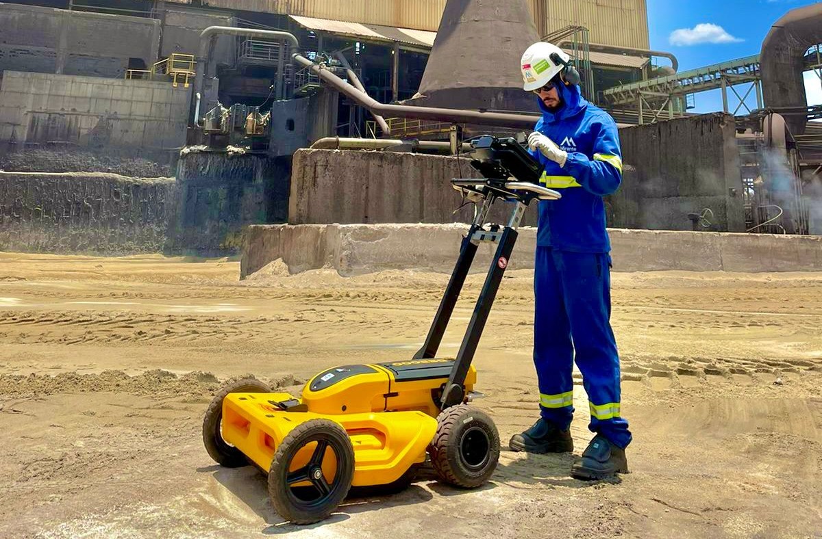 Profissional em equipamento de segurança operando equipamento de georadar em canteiro de obras